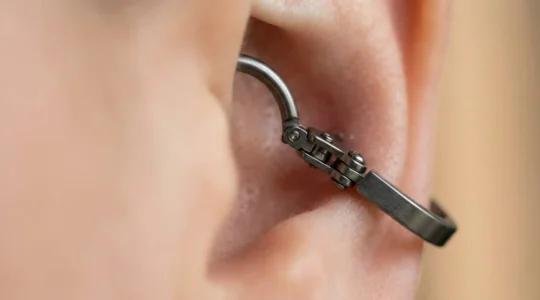 Gros plan sur un anneau clicker en titane posé sur une oreille avec piercing hélix