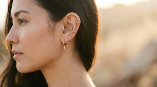 Composition artistique de bijoux sur une oreille percée avec plusieurs piercings dorés