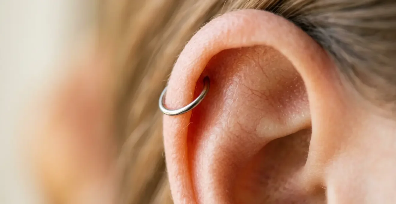 Gros plan sur une oreille avec un piercing hélix en titane brillant sur le cartilage supérieur