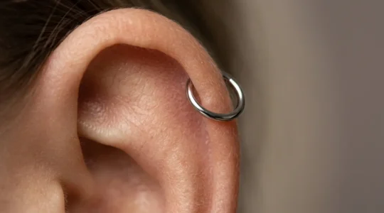 Vue détaillée d'un piercing hélix en titane sur le cartilage supérieur d'une oreille