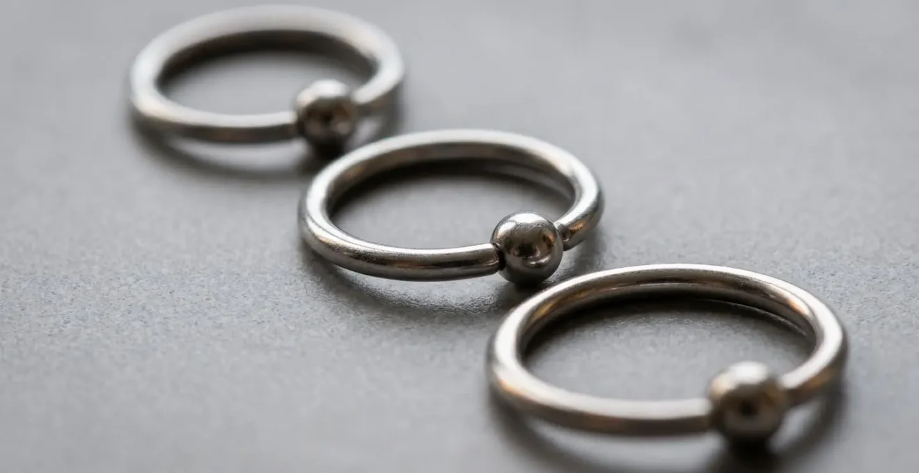 Vue macro de trois anneaux de piercing de diamètres différents sur une surface neutre