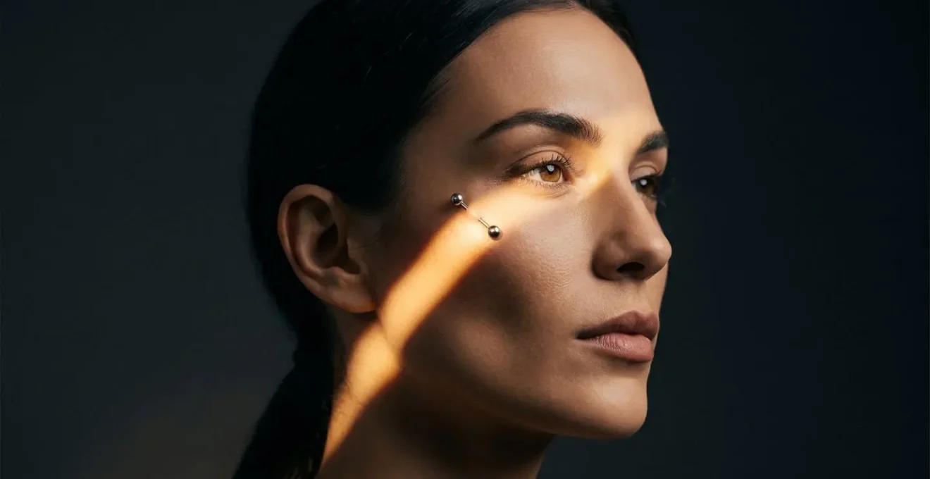 Vue de trois quarts d'un visage montrant l'effet liftant d'un piercing anti-eyebrow positionné stratégiquement sur la pommette