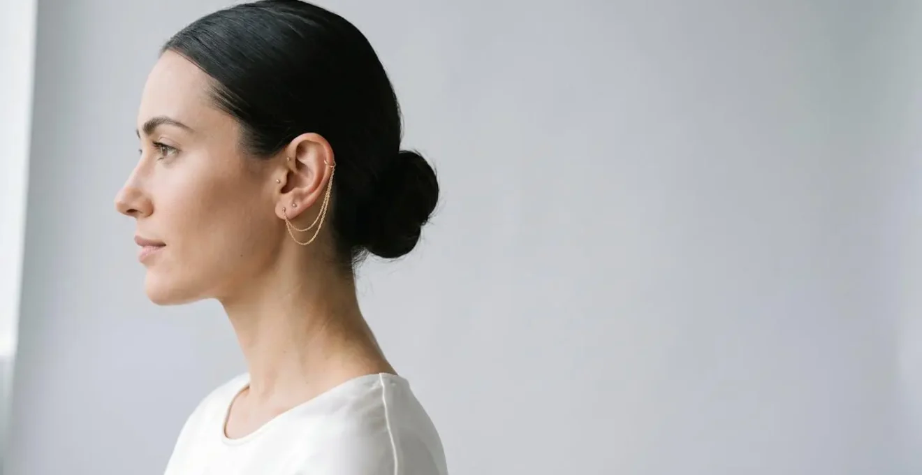 Profil de femme portant une chaîne dorée reliant un earcuff au lobe de l'oreille